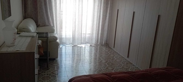 A bedroom with a bed, a bedside table with a lamp, a chair, and a wardrobe.