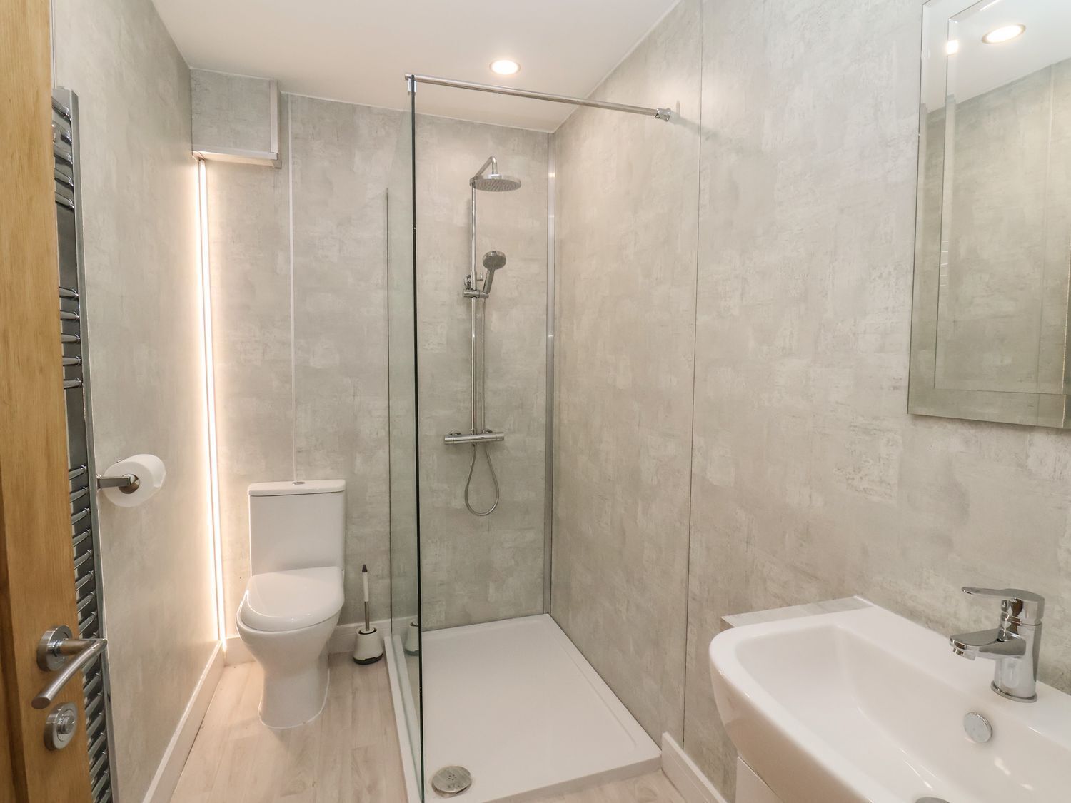 A modern bathroom with a glass-enclosed shower, a toilet, and a sink.