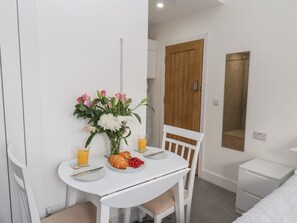 A small, white dining table with a vase of flowers, a plate of food, and a glass of orange juice. - Frankies Seaview 1 (Bridlington)
