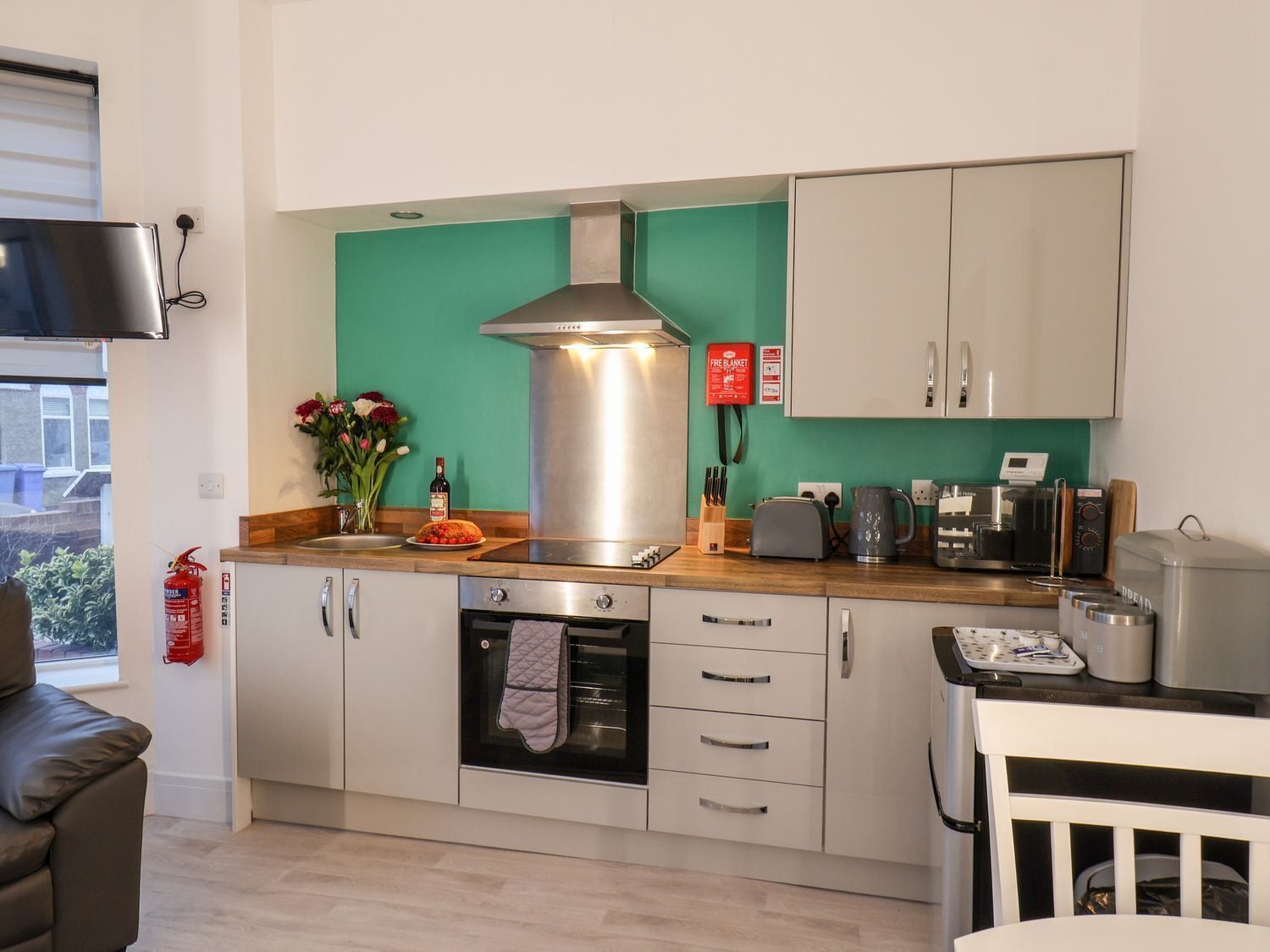 Una cocina moderna con una campana extractora de acero inoxidable, un tostador, una tetera y una cafetera.