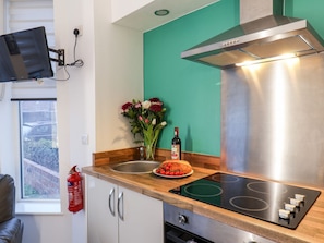 Una cocina moderna con una campana extractora de acero inoxidable, un horno empotrado y una placa de inducción negra.