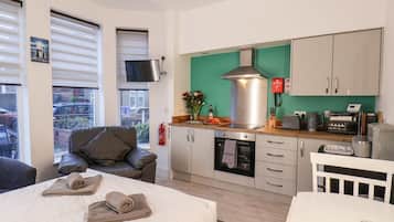 Quarto moderno com uma cama, um sofá, cozinha com fogão e uma televisão.