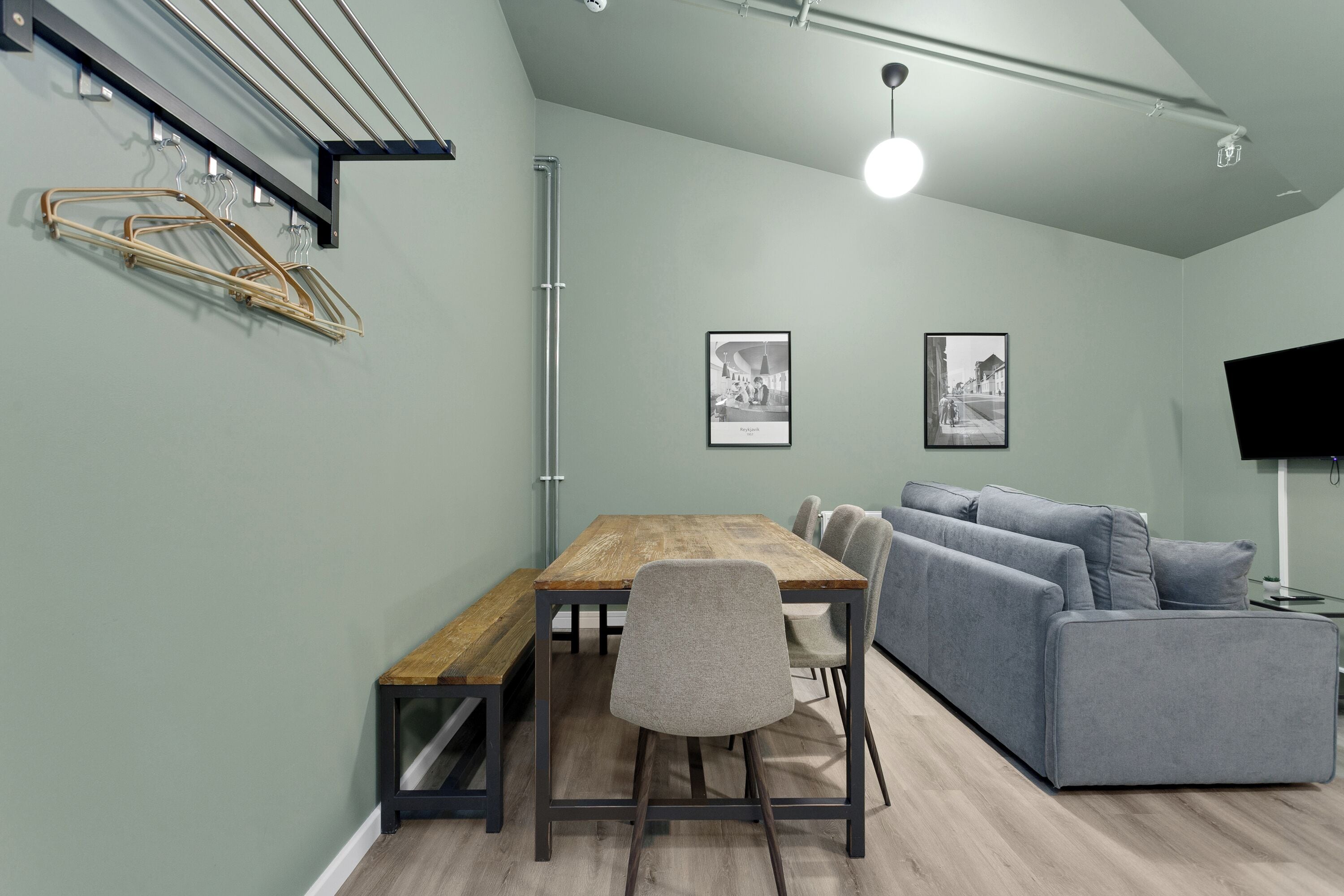 Ein modernes Wohnzimmer mit einem Holzesstisch, einem grauen Sofa und einem an der Wand befestigten Fernseher.