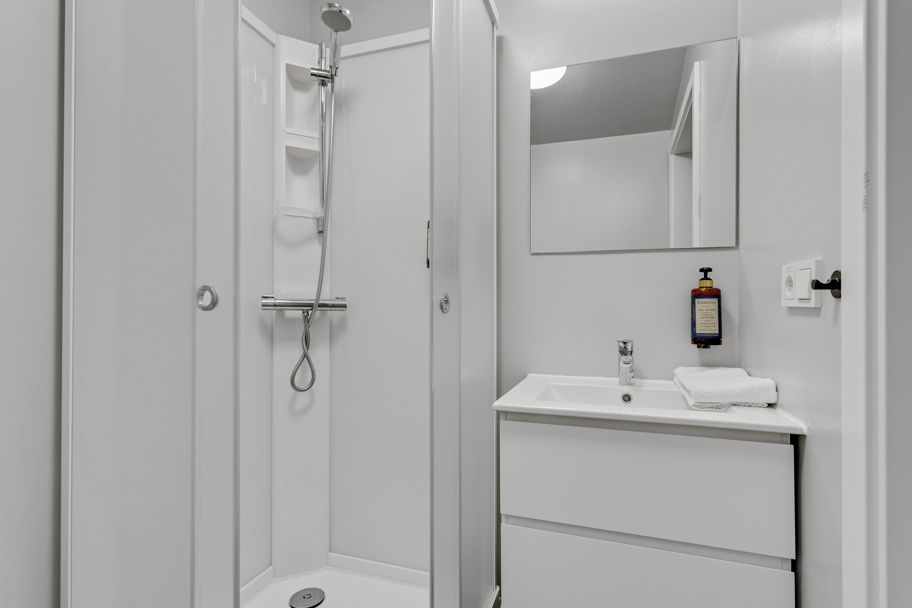 Ein Badezimmer mit Dusche, Waschbecken, Spiegel und Handtuchhalter.
