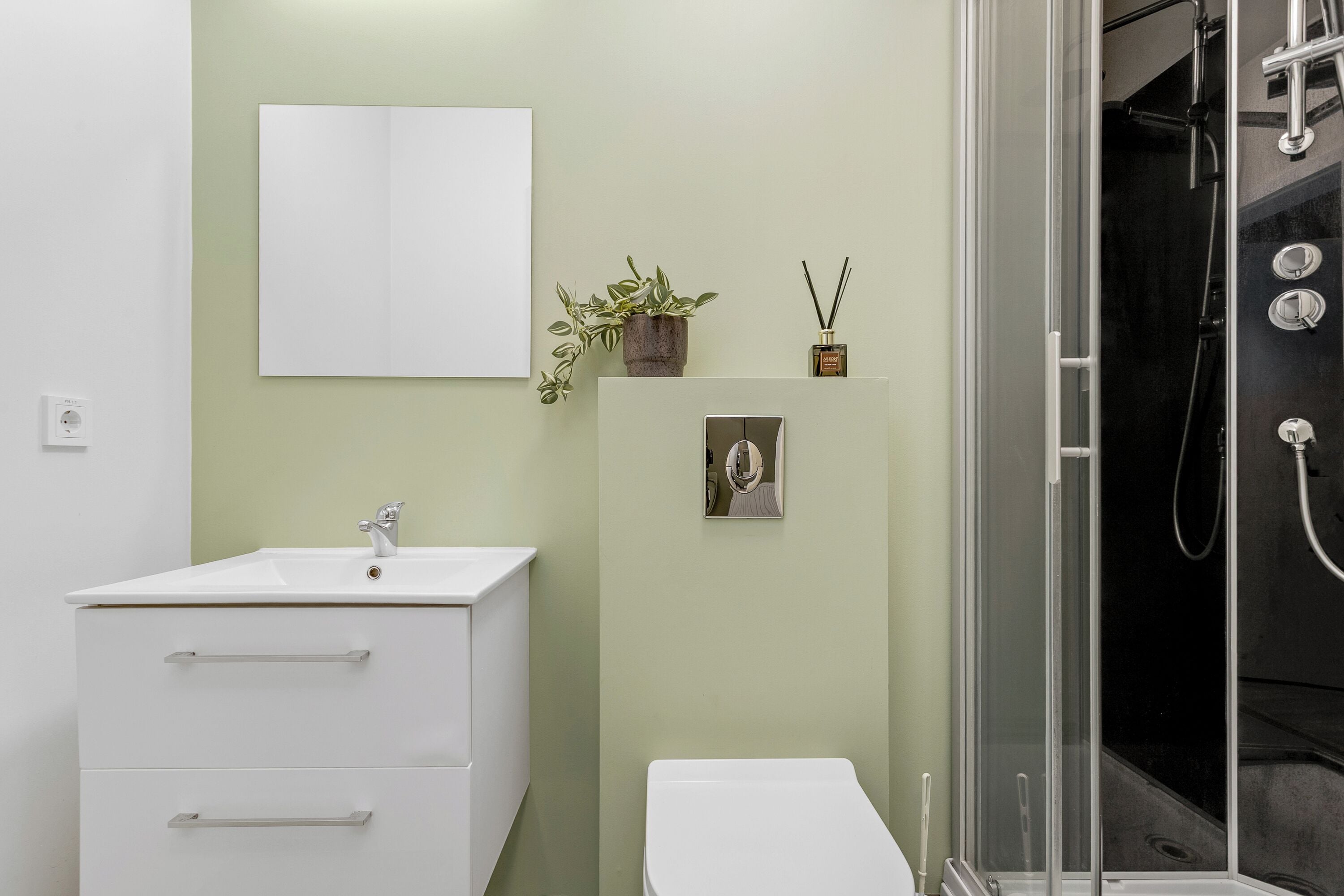 A bathroom with a white sink, a toilet, a shower enclosure, and a wall-mounted mirror.