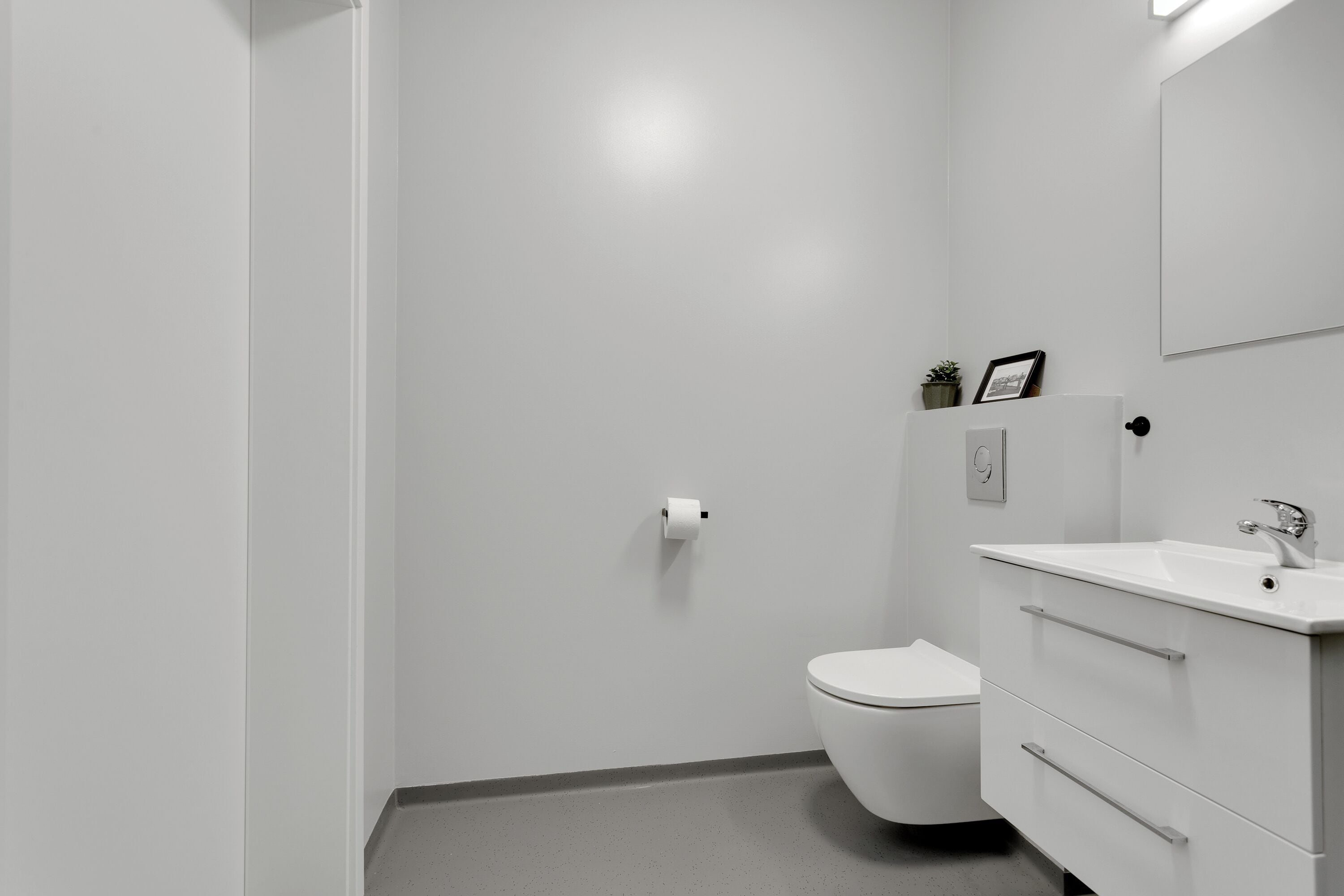 A modern bathroom with a toilet, sink, and mirror.