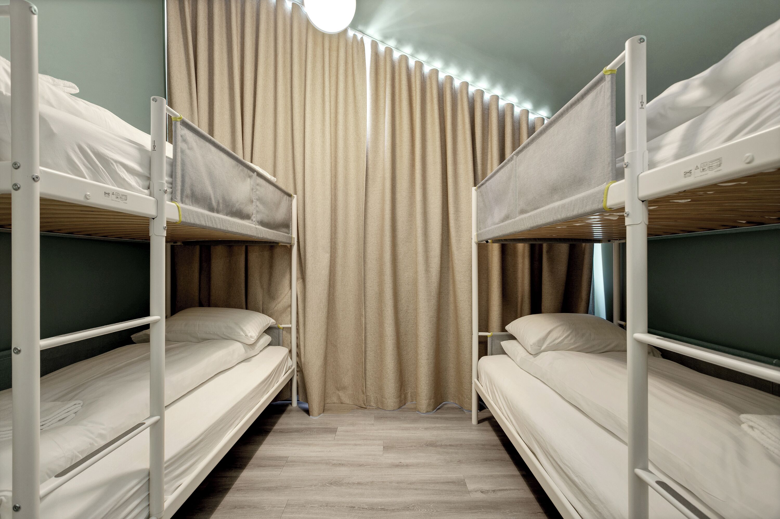 A room with bunk beds, a curtain, and a wooden floor.