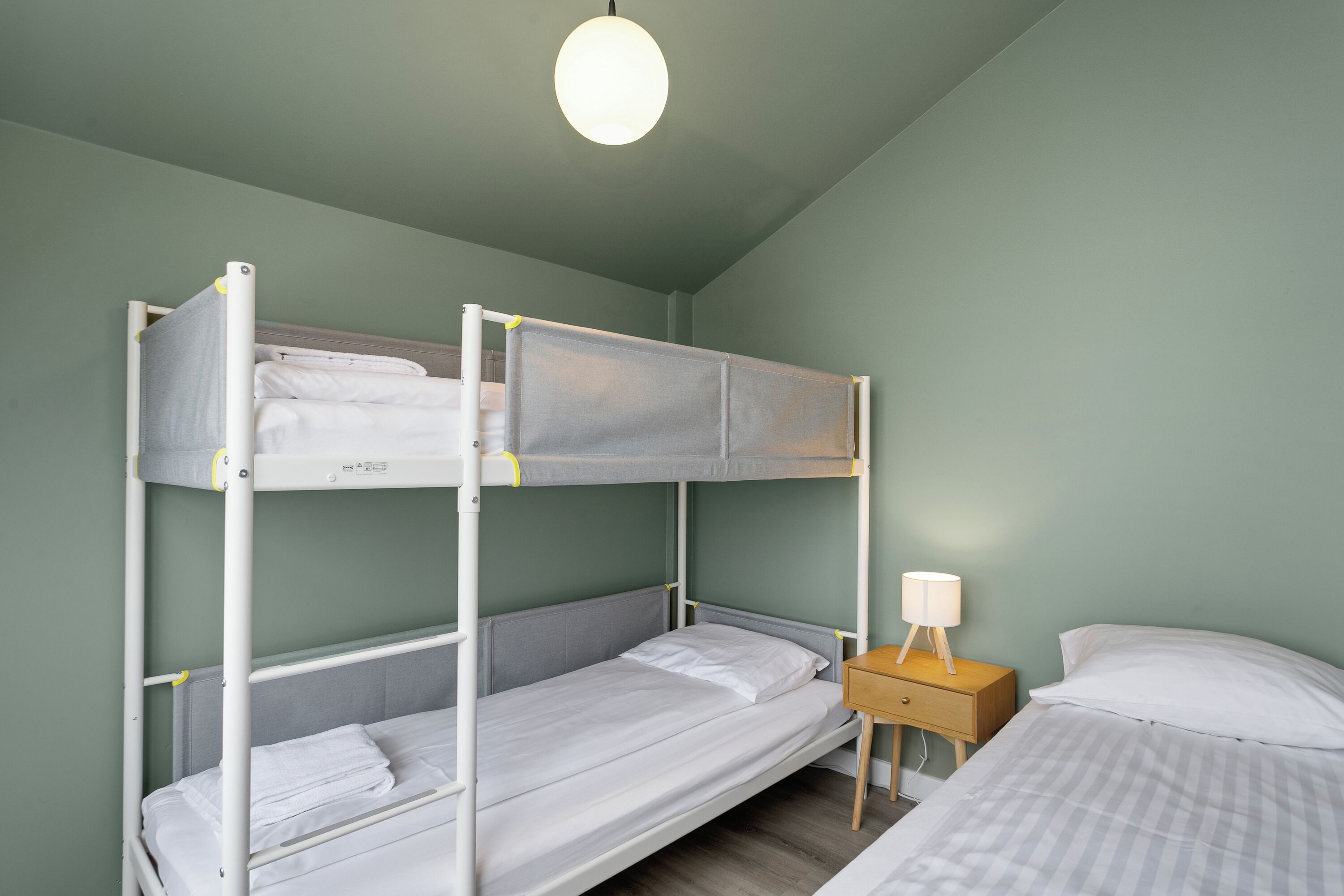 A bunk bed room with a bedside table and lamp.
