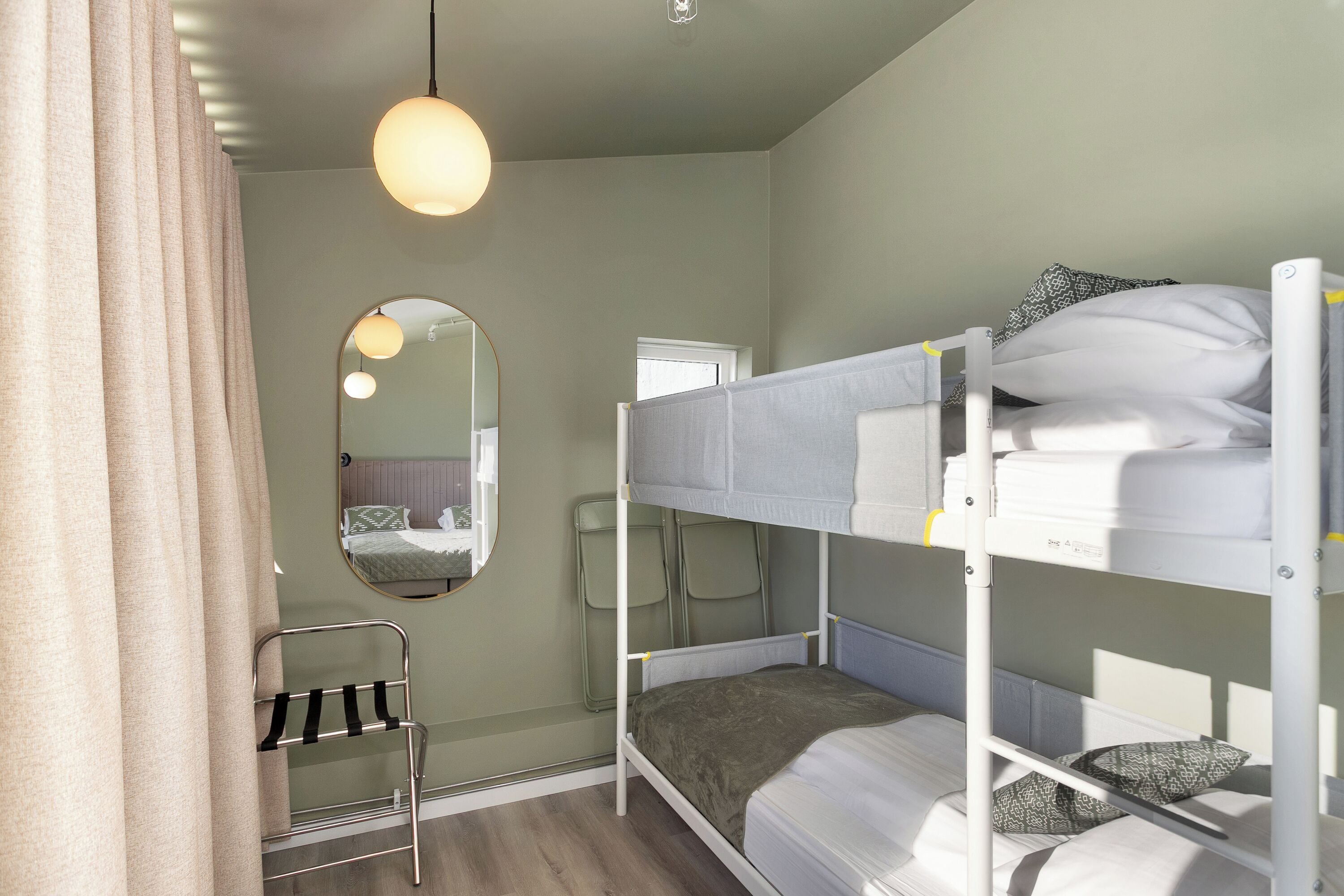 Quarto com beliche, espelho, luminária pendente e uma cadeira.