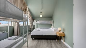 A room with bunk beds, a bedside table with a lamp, and a window with curtains.