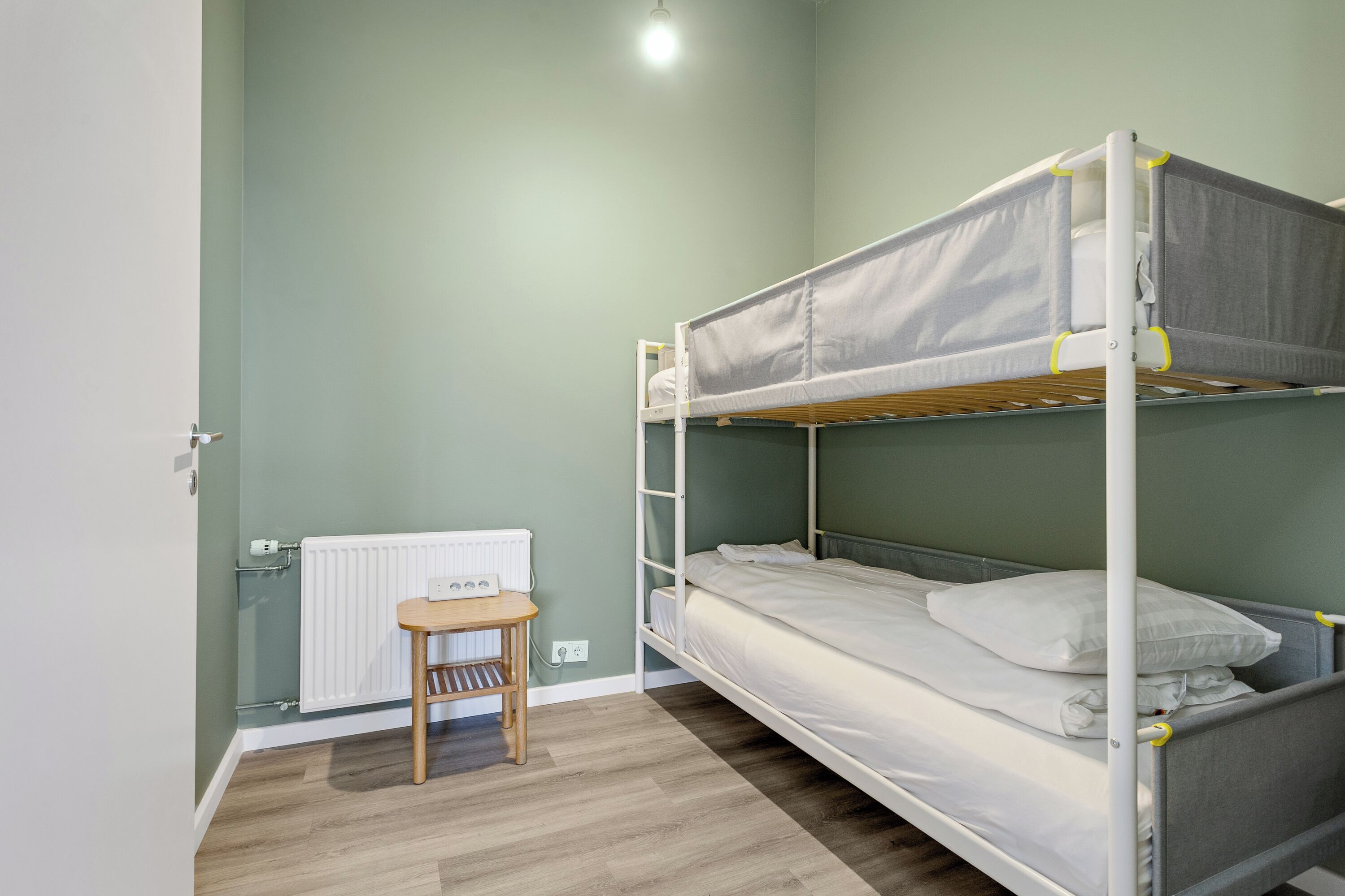 Dormitorio con literas, una mesa de madera y un radiador.