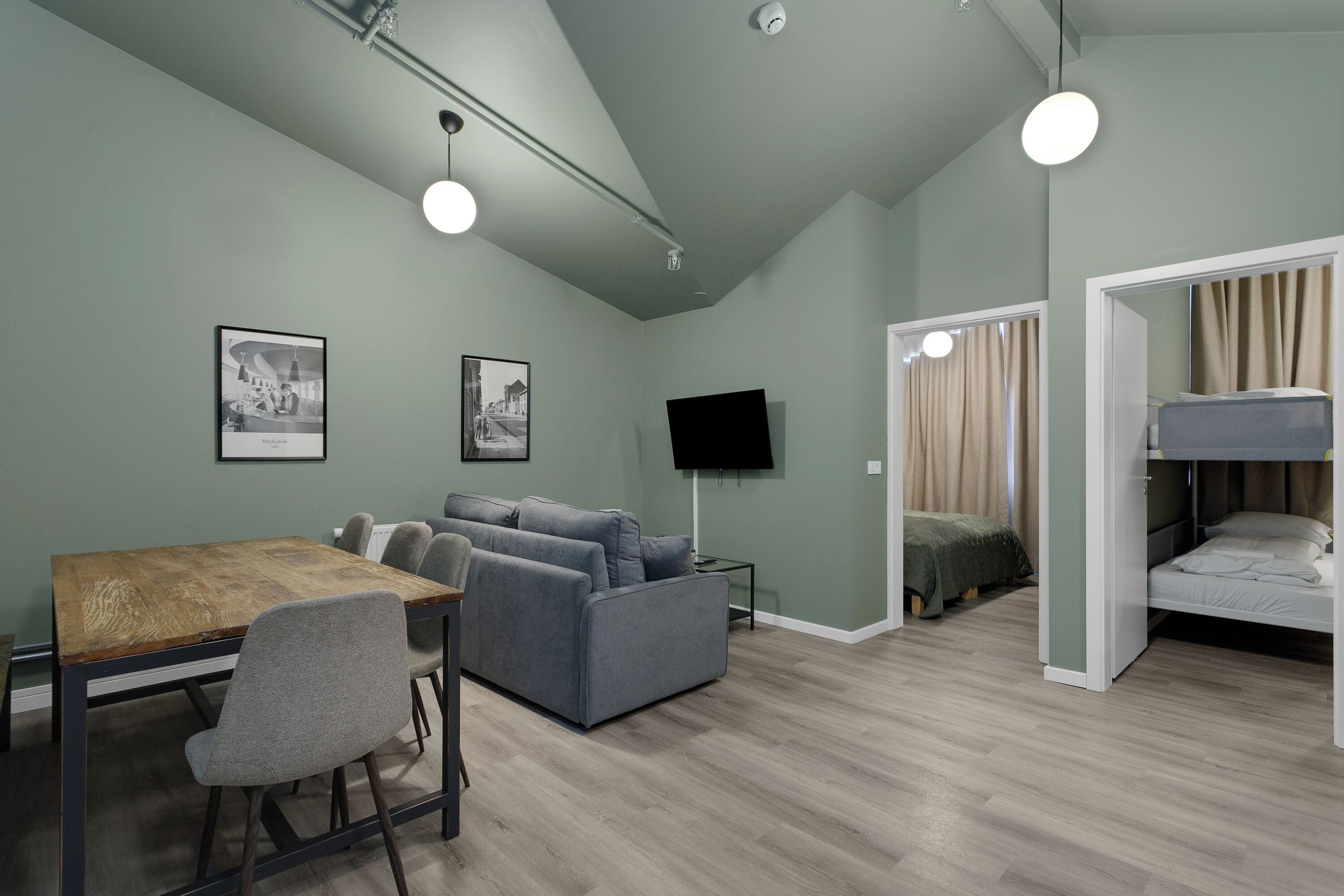 Quarto moderno com mesa de jantar, sofás, televisão e beliche.