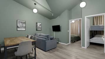 Ein modernes Zimmer mit Esstisch, Sofas, Fernseher und einem Stockbett.