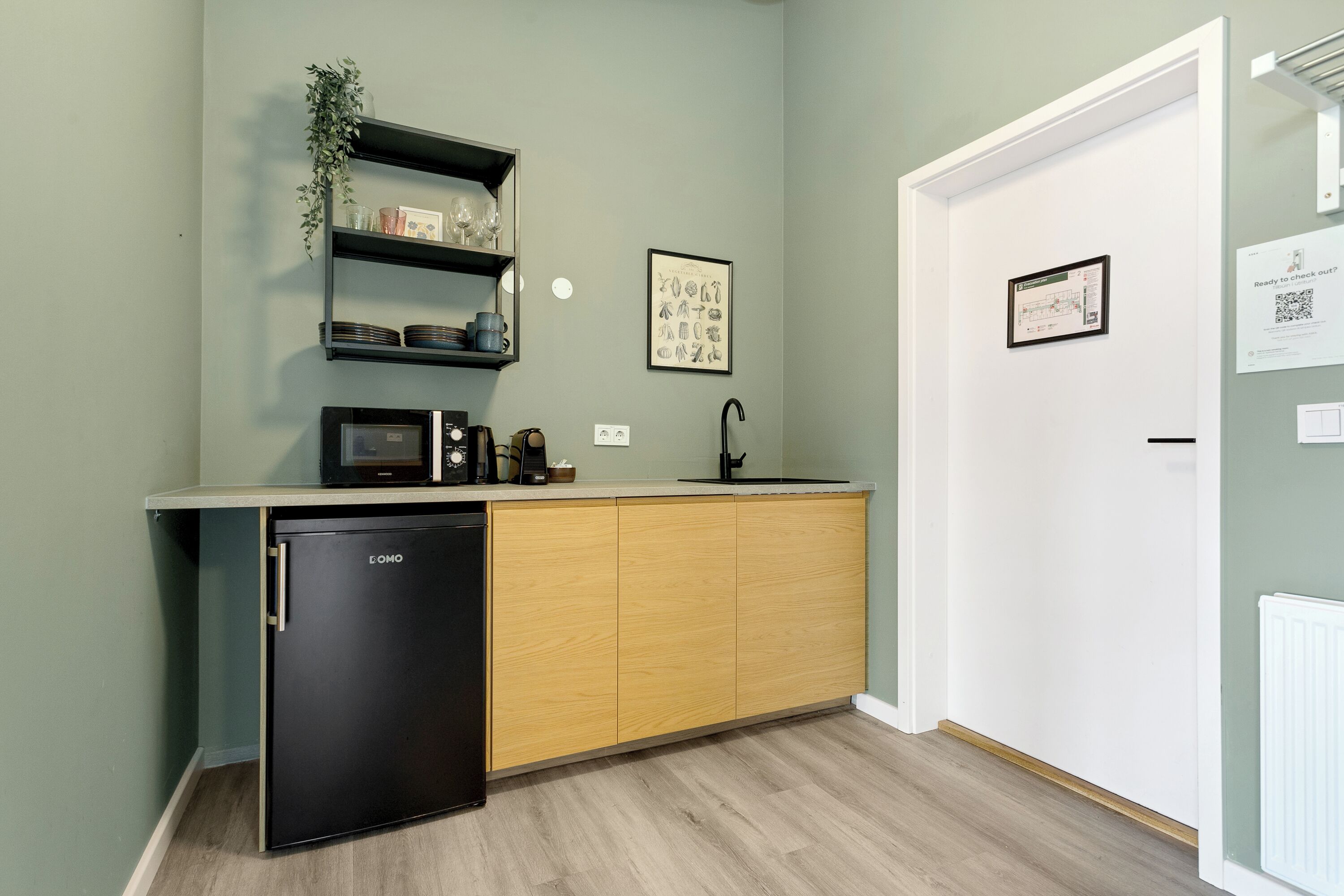 A compact kitchen with a black refrigerator, wooden cabinets, a microwave, and a small countertop.