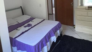 Un dormitorio con cama, cómoda y puerta que da a otra habitación.