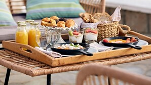 Una bandeja de desayuno con comida y bebidas sobre una mesa de mimbre.