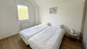 Ein Schlafzimmer mit Bett, Fenster, Heizkörper, Lampe und einem Bild an der Wand.