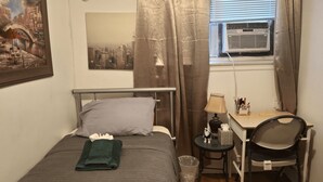 A neatly arranged bedroom with a bed, a desk, a chair, and a window with an air conditioner. - Tranquil 1-bedroom apartment share with AC in vibrant Brooklyn Near B8 Bus Stop (Brooklyn)