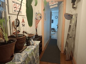 Ein Korridor mit einem Tisch voller Topfpflanzen, einem Schild mit der Aufschrift 'Welcome to Paradise', einem 'Nichtraucher'-Schild und einem Schild für die '1. Etage'.
