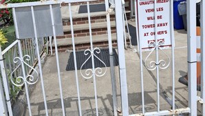 A gated entrance with a warning sign, a brick house with a red door, and a staircase leading to a porch. - Tranquil 1-bedroom apartment share with AC in vibrant Brooklyn Near B8 Bus Stop (Brooklyn)