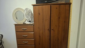 A wooden wardrobe with a mirror and a fan on top, a small desk with a lamp, and a door with a handle. - Tranquil 1-bedroom apartment share with AC in vibrant Brooklyn Near B8 Bus Stop (Brooklyn)