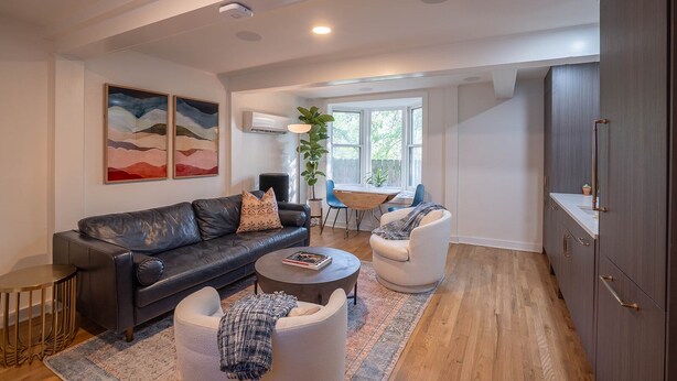 A modern living room with a leather sofa, a round coffee table, and a dining area with a table and chairs. - Travis Heights Gem! Walk to Lady Bird Lake & SoCo (Austin)