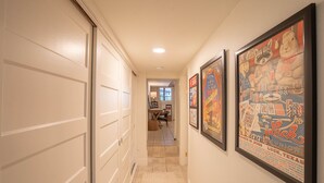 A hallway with white walls and a tiled floor, leading to a room with a desk and chair. - Travis Heights Gem! Walk to Lady Bird Lake & SoCo (Austin)