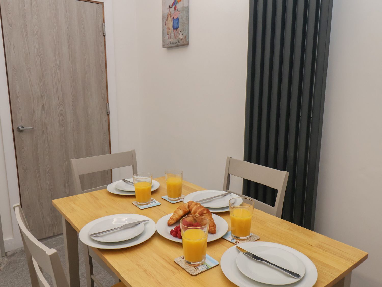A breakfast table set with plates, croissants, and glasses of orange juice.