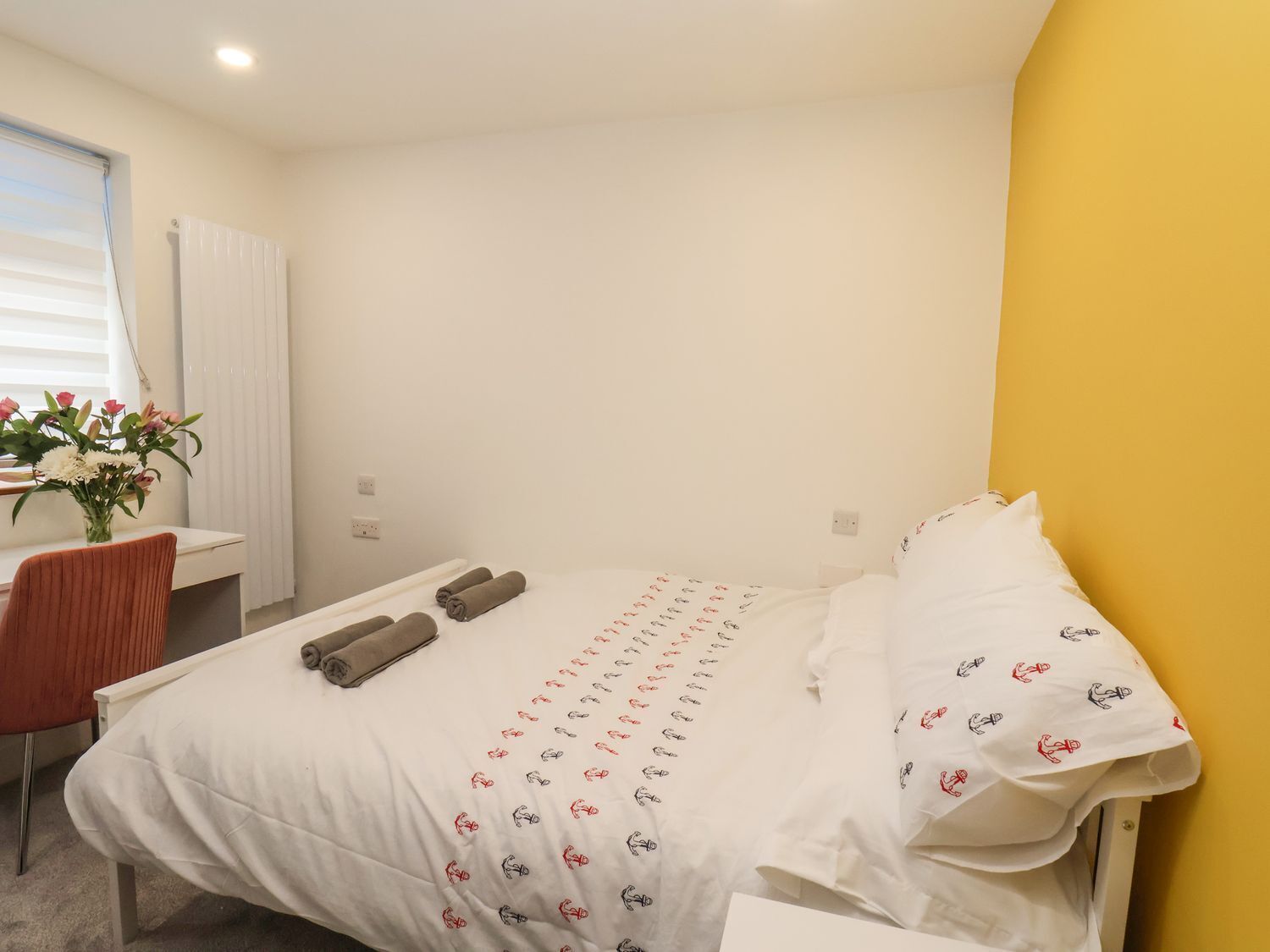 A hotel room with a bed, a desk, and a chair.