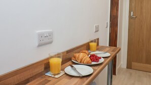 A breakfast setup with a wooden counter, a glass of orange juice, a croissant, and a plate of raspberries. - Frankies Seaview 4 (Bridlington)