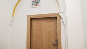 A wooden door with a keyhole, a white wall, and a yellow arch above it. - Frankies Seaview 4 (Bridlington)