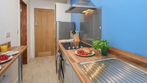A modern kitchen with a stainless steel range hood, wooden countertops, a built-in oven, and a small window. - Frankies Seaview 4 (Bridlington)