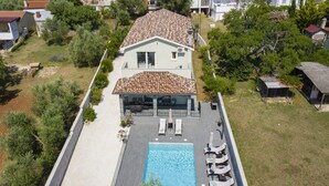 Ein Haus mit Swimmingpool, Liegestühlen und einer überdachten Terrasse.