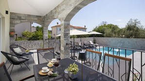 Eine Dachterrasse mit Pool, Sitzgelegenheiten im Freien und einem steinernen Bogen.