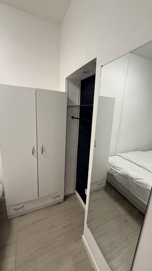 Ein Schlafzimmer mit einem Bett, einem Kleiderschrank und einem Spiegel.