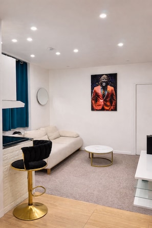 Ein modernes Wohnzimmer mit einer Couch, einem runden Tisch, einem Sessel, einem Gemälde und einem Spiegel an der Wand.