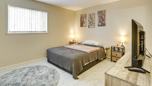 Een slaapkamer met een bed, nachtlampjes, een televisie en kunst aan de muur.