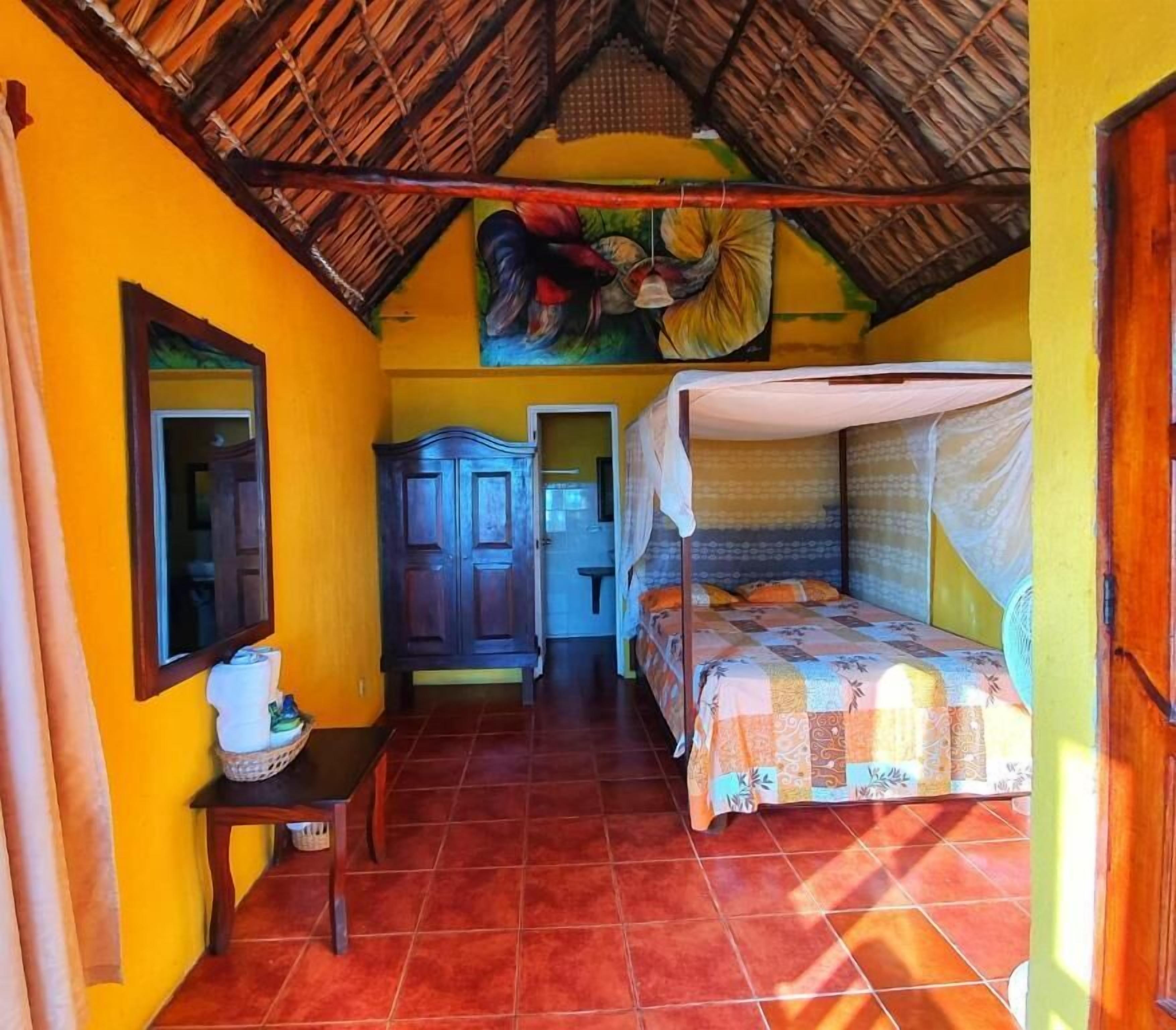 A room with a bed, a wardrobe, a mirror, and a painting on the wall.