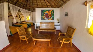 A room with a thatched roof, wooden furniture, a painting on the wall, and a window with curtains. - Hotel Cafe Del Sol (Monterrico)