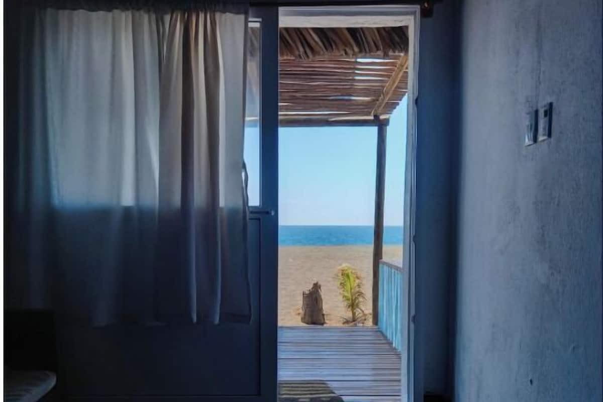 Una habitación con vista al mar, una puerta que da al exterior y una planta pequeña en la terraza.