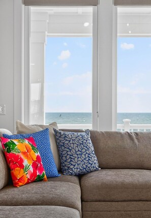 Een woonkamer met uitzicht op de oceaan door grote ramen.