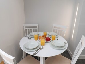 A round dining table with white chairs, plates, cutlery, glasses of orange juice, a croissant, and raspberries. - Frankies Seaview 5 (Bridlington)
