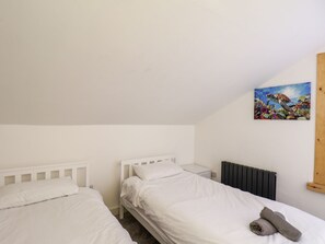 A bedroom with two single beds, a radiator, and a painting on the wall. - Frankies Seaview 5 (Bridlington)