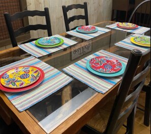 A dining table with colorful placemats and plates, surrounded by chairs. - Lake Front Retreat - Pool Table, Golf Cart, Kayaks (Lampe)