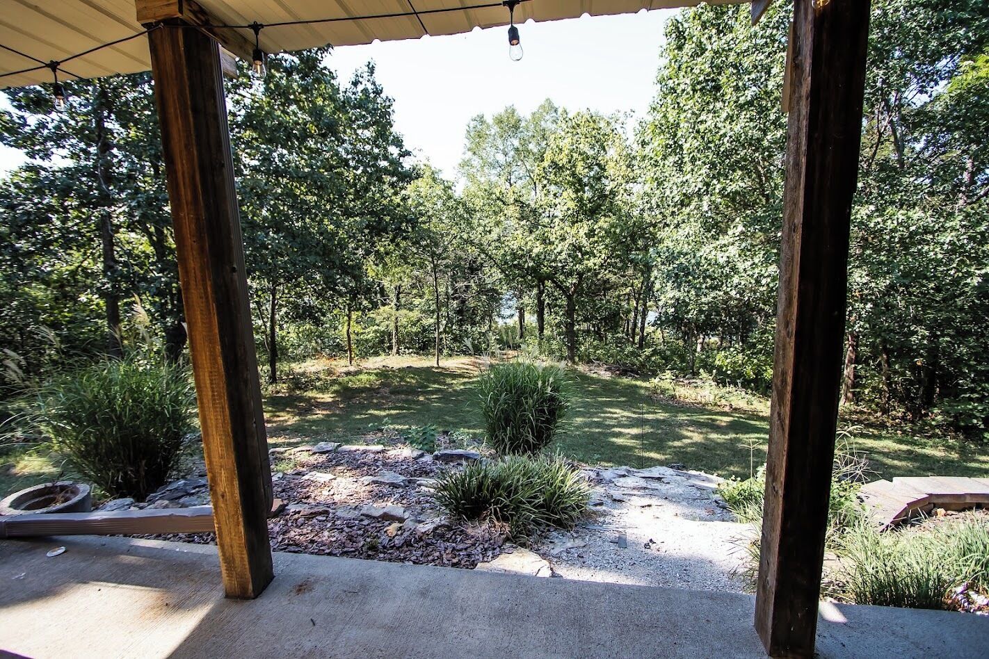 Un espace extérieur abrité, avec un chemin en béton menant à une pelouse verdoyante entourée d’arbres.