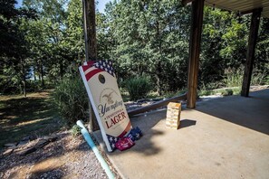 A beer pong table with a Yuengling Lager sign, surrounded by trees and a covered area. - Lake Front Retreat - Pool Table, Golf Cart, Kayaks (Lampe)