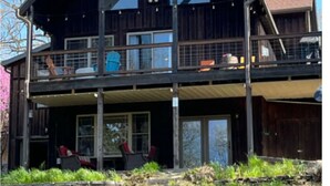 Ein zweistöckiges Holzhaus mit Balkon, großen Fenstern und einem Steinfundament.