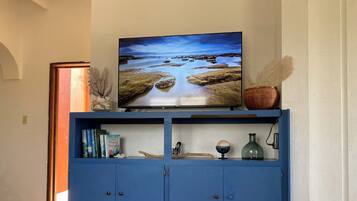 A blue cabinet with a television on top, books, a bowl, and decorative items.