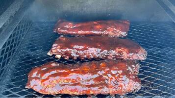 Three ribs cooking on a grill.