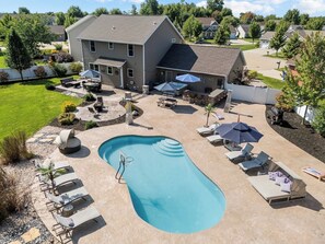 Ein Garten mit Swimmingpool, Liegestühlen und Grillplatz.